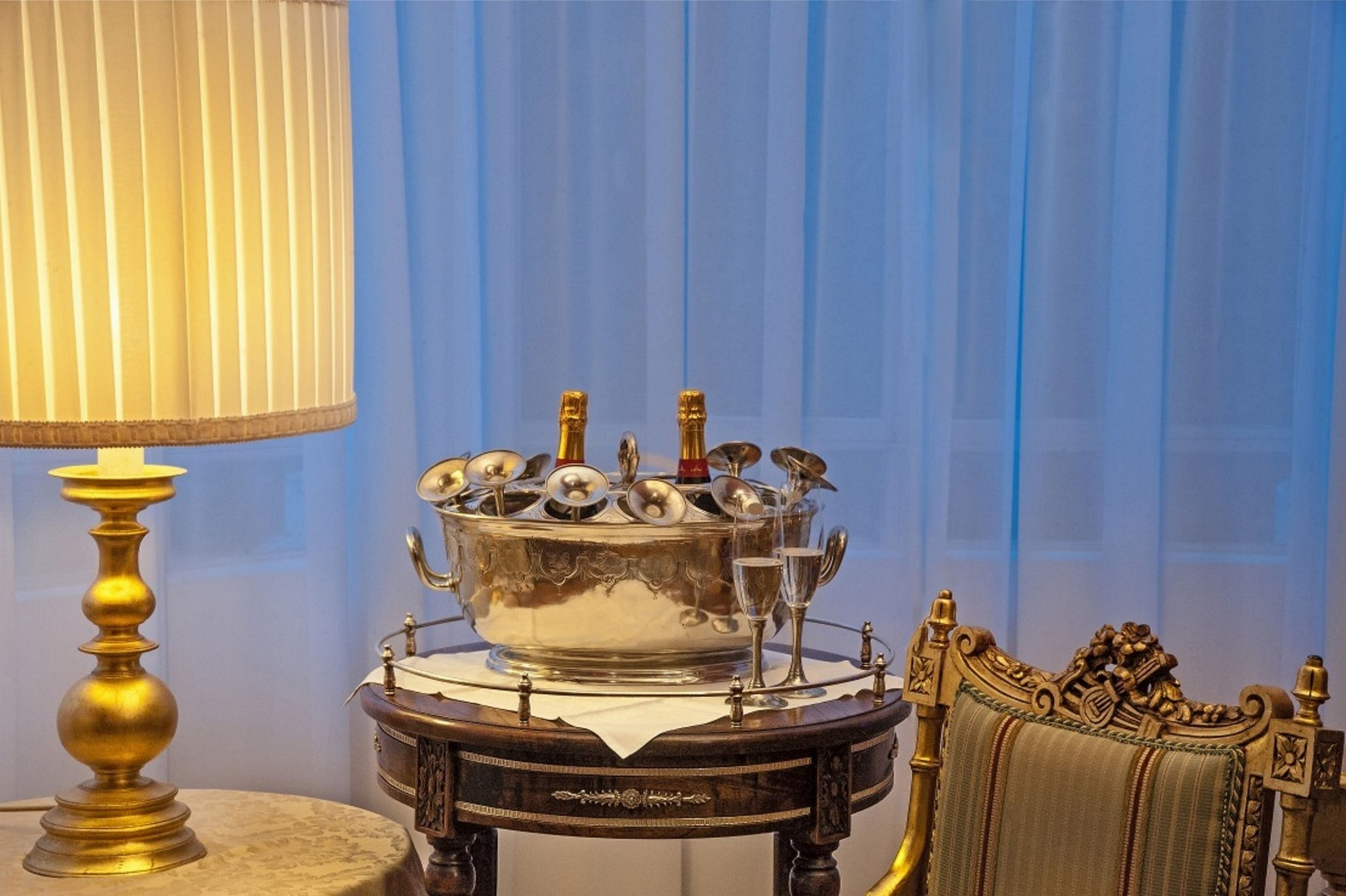 Une pièce avec une table mise pour un repas, une lampe décorative et une chaise aux motifs ouvragés.