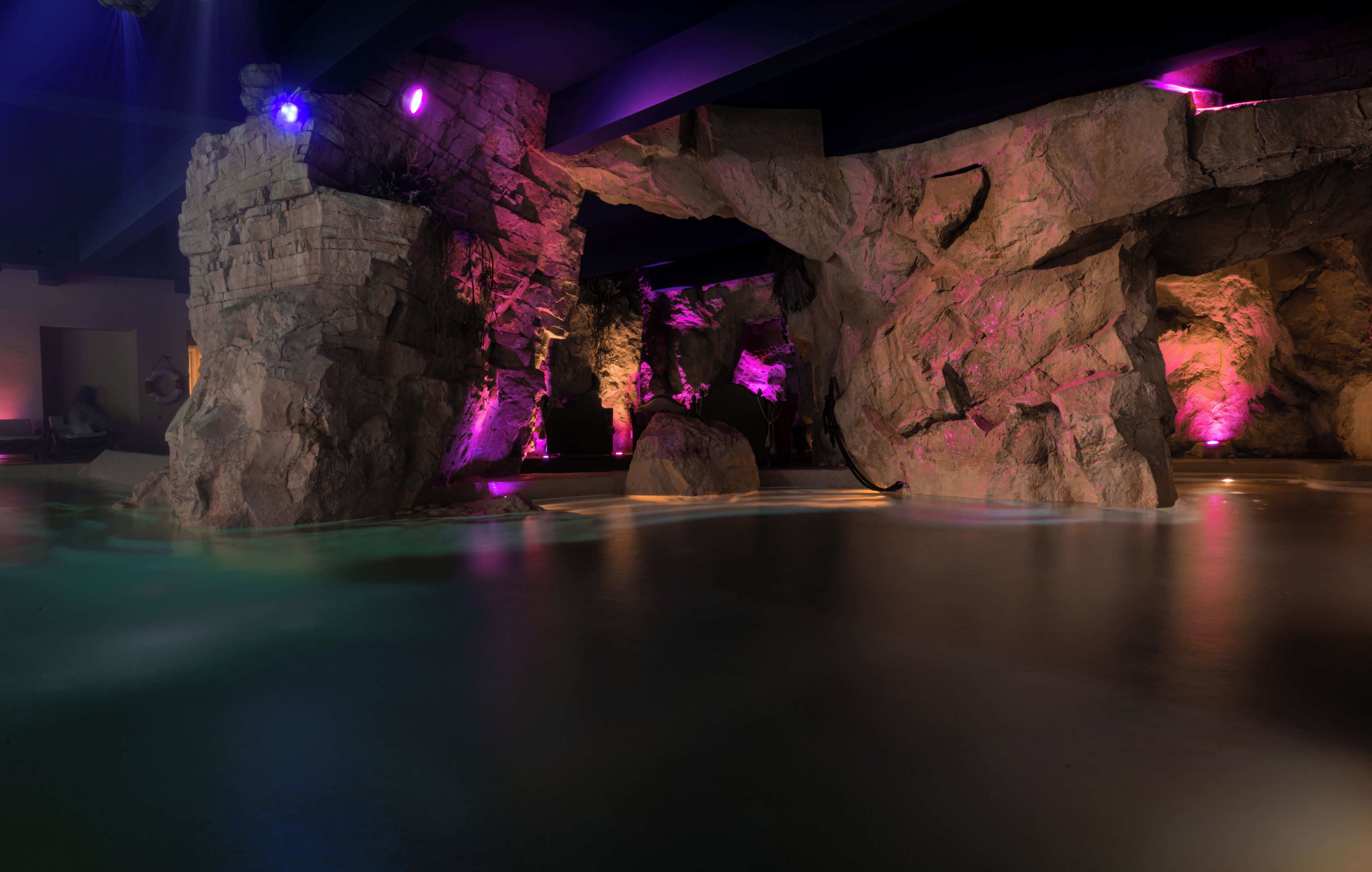 A rock formation with a pool in front.