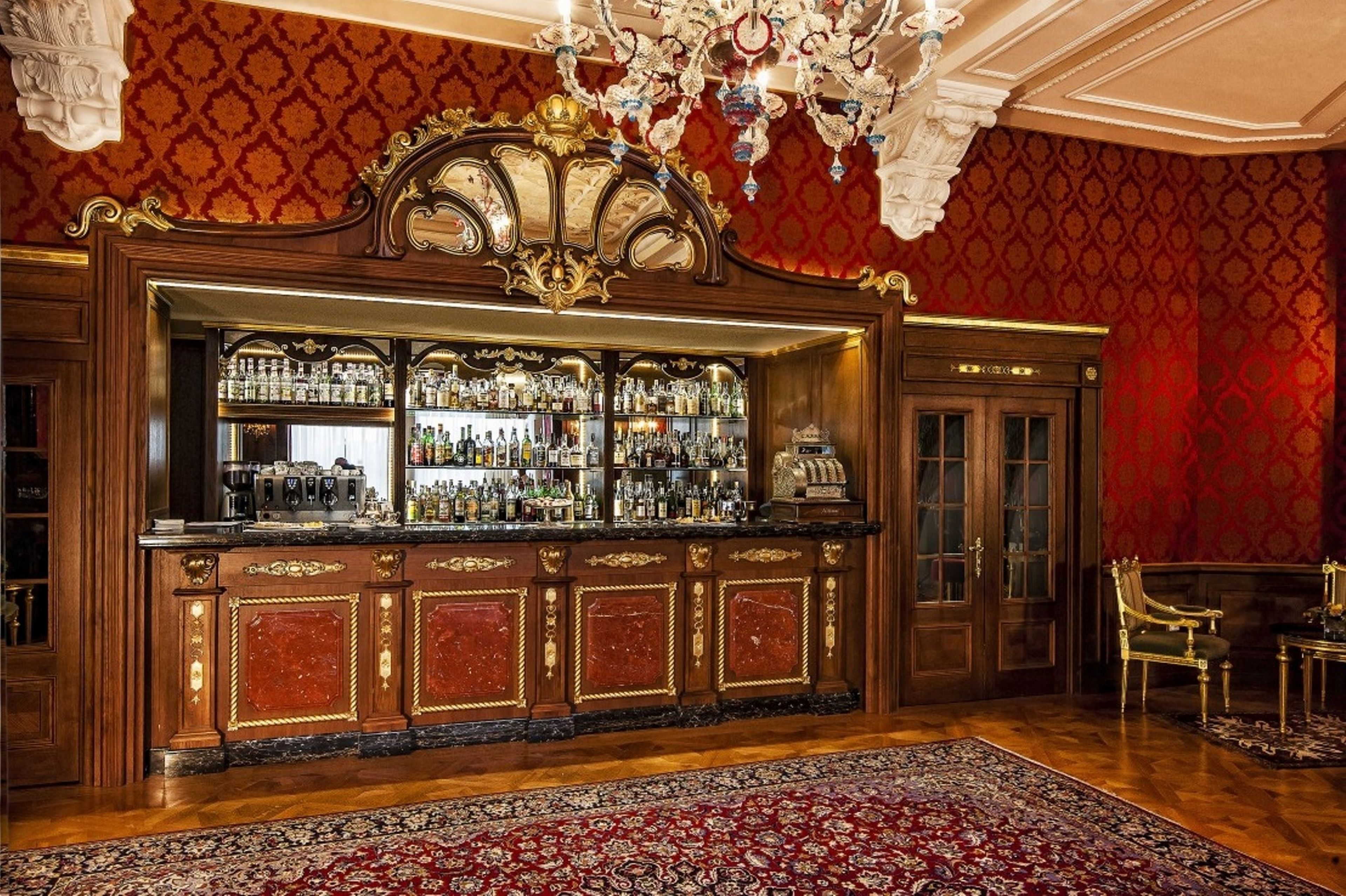 Uma área de bar com balcão de madeira, prateleiras com garrafas e um candelabro.
