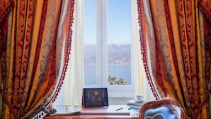 Una habitación con escritorio, una silla y vistas a un lago y montañas a través de una ventana.