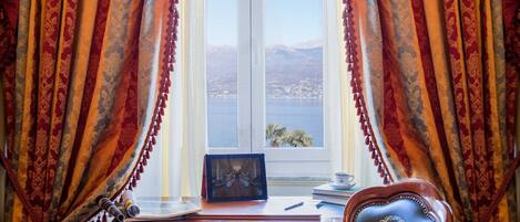 A room with a desk, a chair, and a view of a lake and mountains through a window.