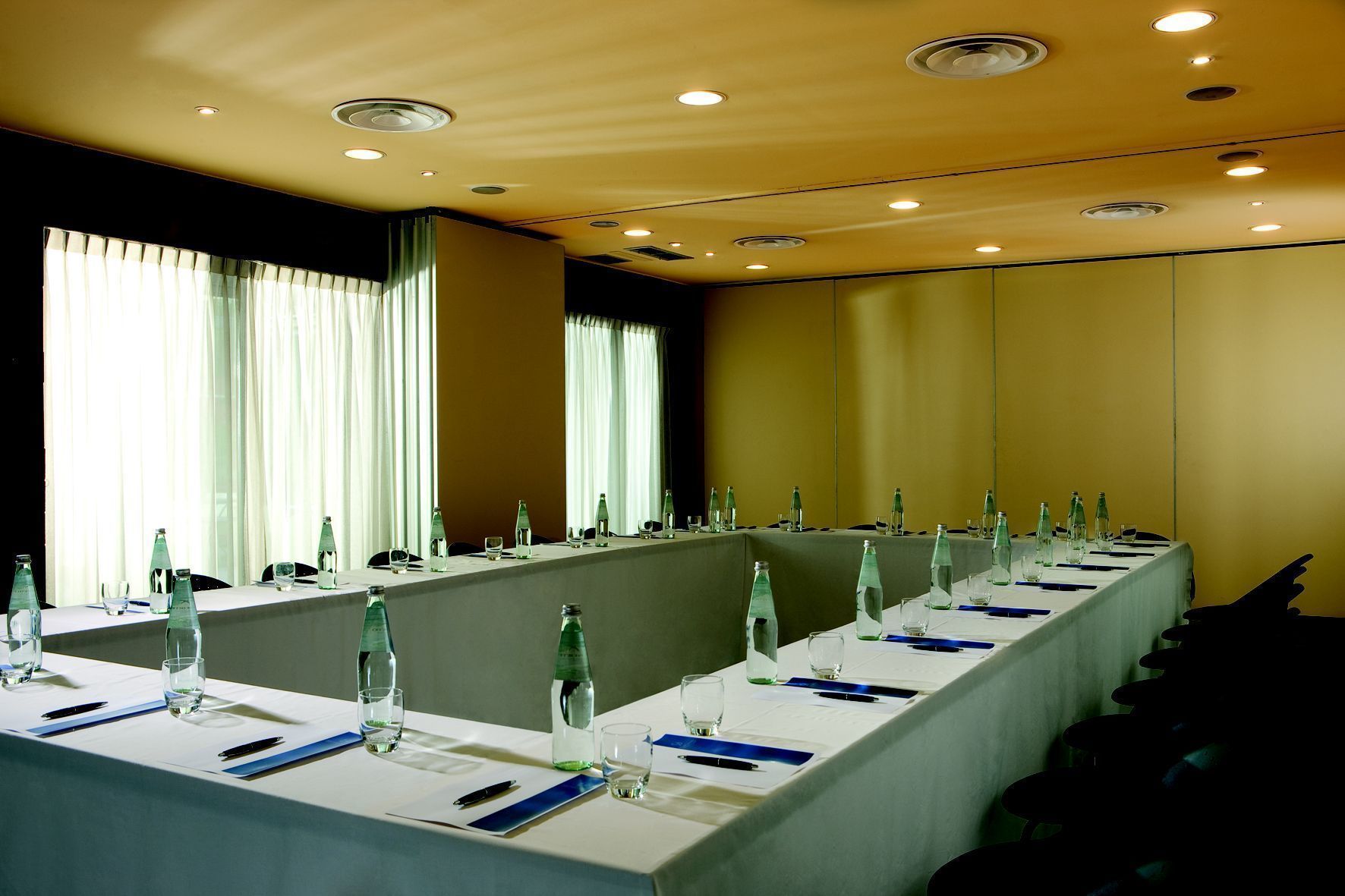 Ein Konferenzraum mit langen Tischen, Stühlen und Wasserflaschen.