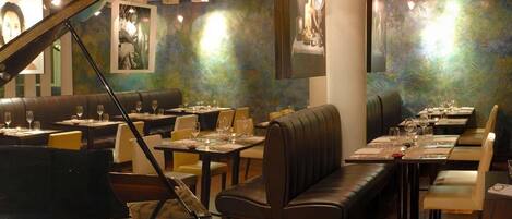 A restaurant with a grand piano, booths, and tables set for dining.