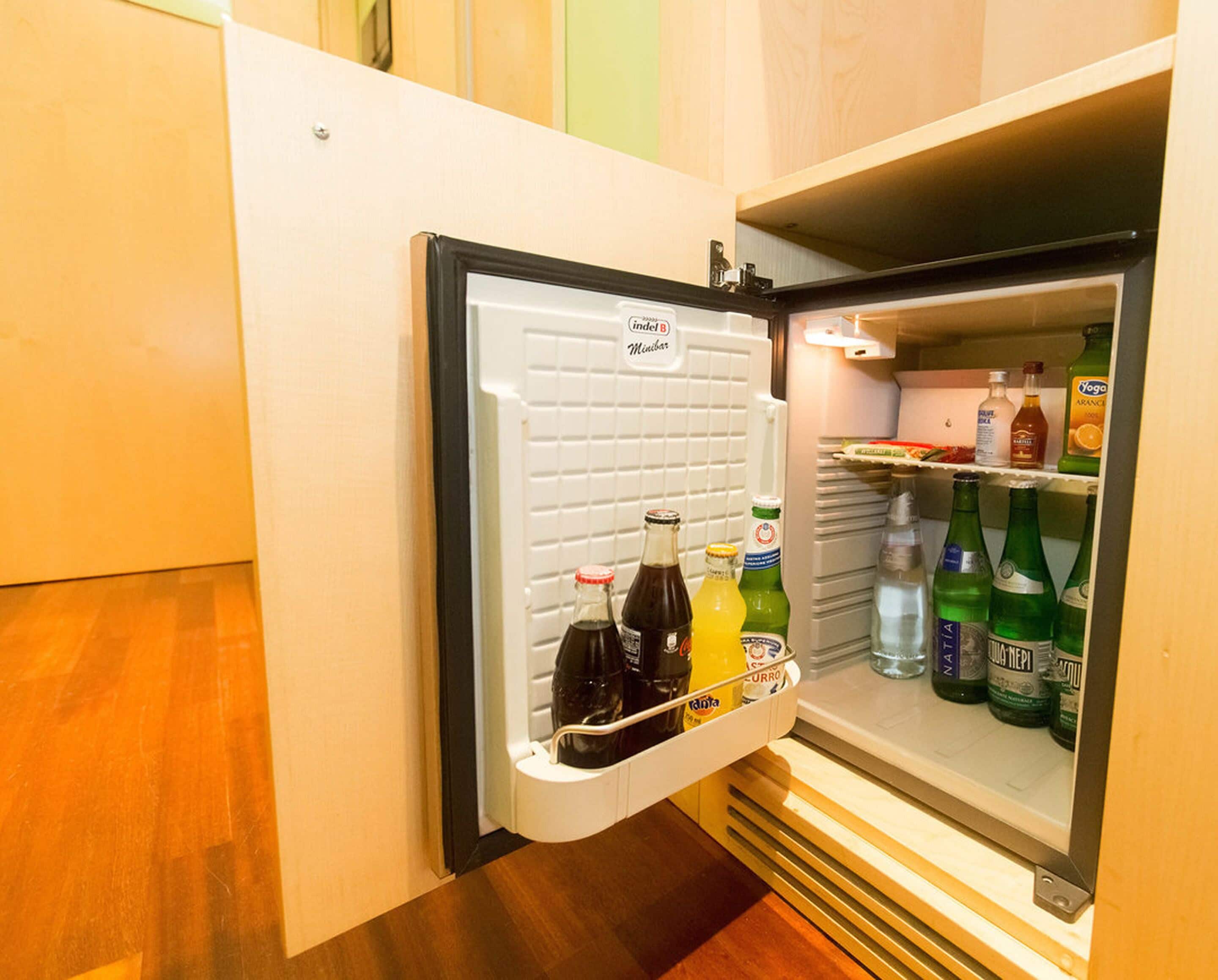 A mini-fridge with a variety of beverages including sodas, juices, and water.
