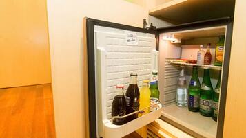 A mini-fridge with a variety of beverages including sodas, juices, and water.