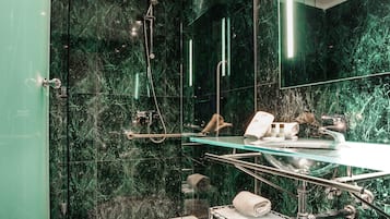 Un bagno moderno con box doccia in vetro, pavimento in marmo e un mobile lavabo con piano in vetro.