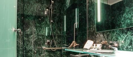 A modern bathroom with a glass shower enclosure, a marble-tiled floor, and a vanity with a glass countertop.