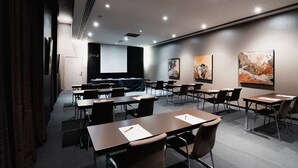 Una sala de conferencias moderna con una larga mesa, sillas, una pantalla de proyector y arte abstracto en las paredes.