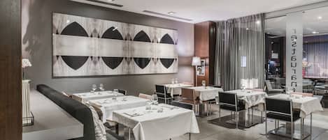 A modern restaurant with white tablecloths, black and white abstract wall art, and a clean, contemporary design.