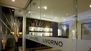 Un moderno vestíbulo de hotel con una recepción que dice "MAX HOTEL LIVORNO".