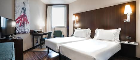 A hotel room with two beds, a desk with a chair, a television, and a large window.