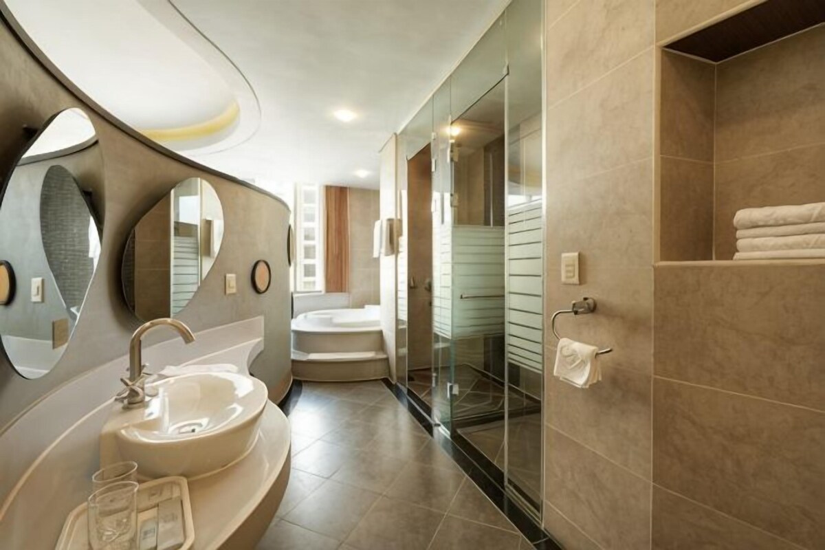 A modern bathroom with a sink, mirror, and glass shower enclosure.