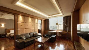 Una habitación de hotel moderna con piso de madera, sofás de cuero, una mesa de centro, un televisor y vista a la ciudad.