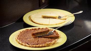 Two pies on yellow plates on a black countertop.