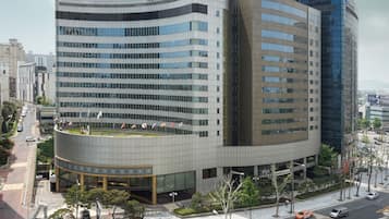 A modern hotel with a curved facade, multiple floors, and a prominent entrance.