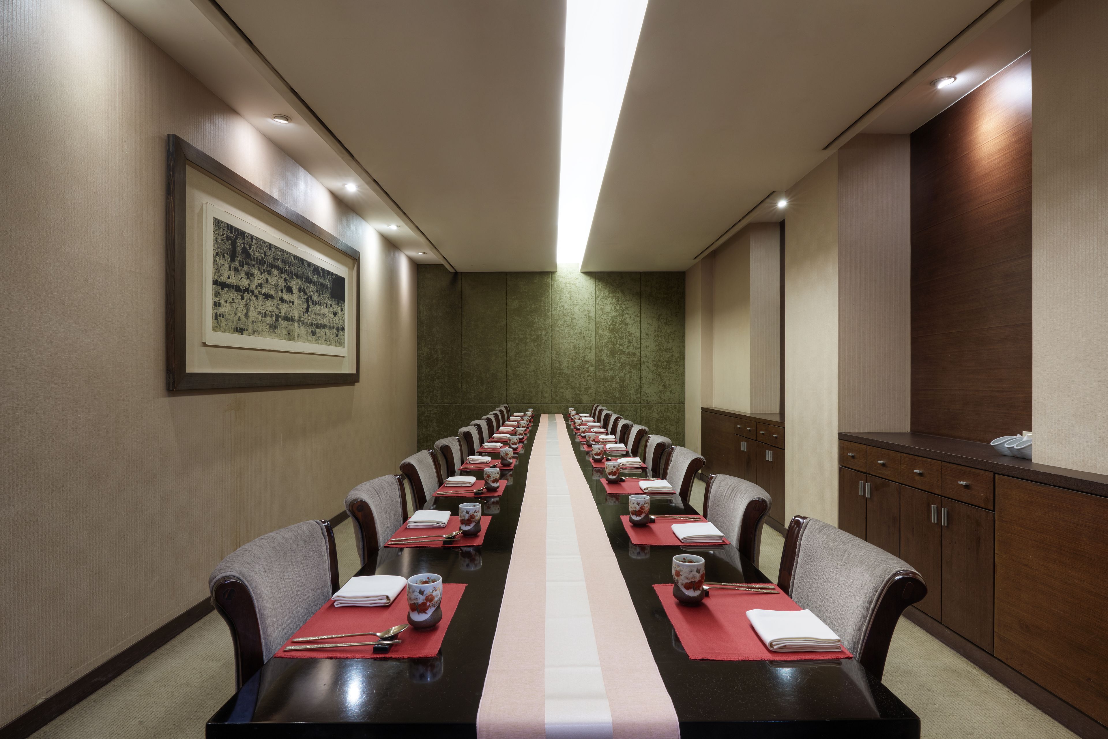 Un salón de conferencias con una larga mesa, sillas y un cuadro en la pared.