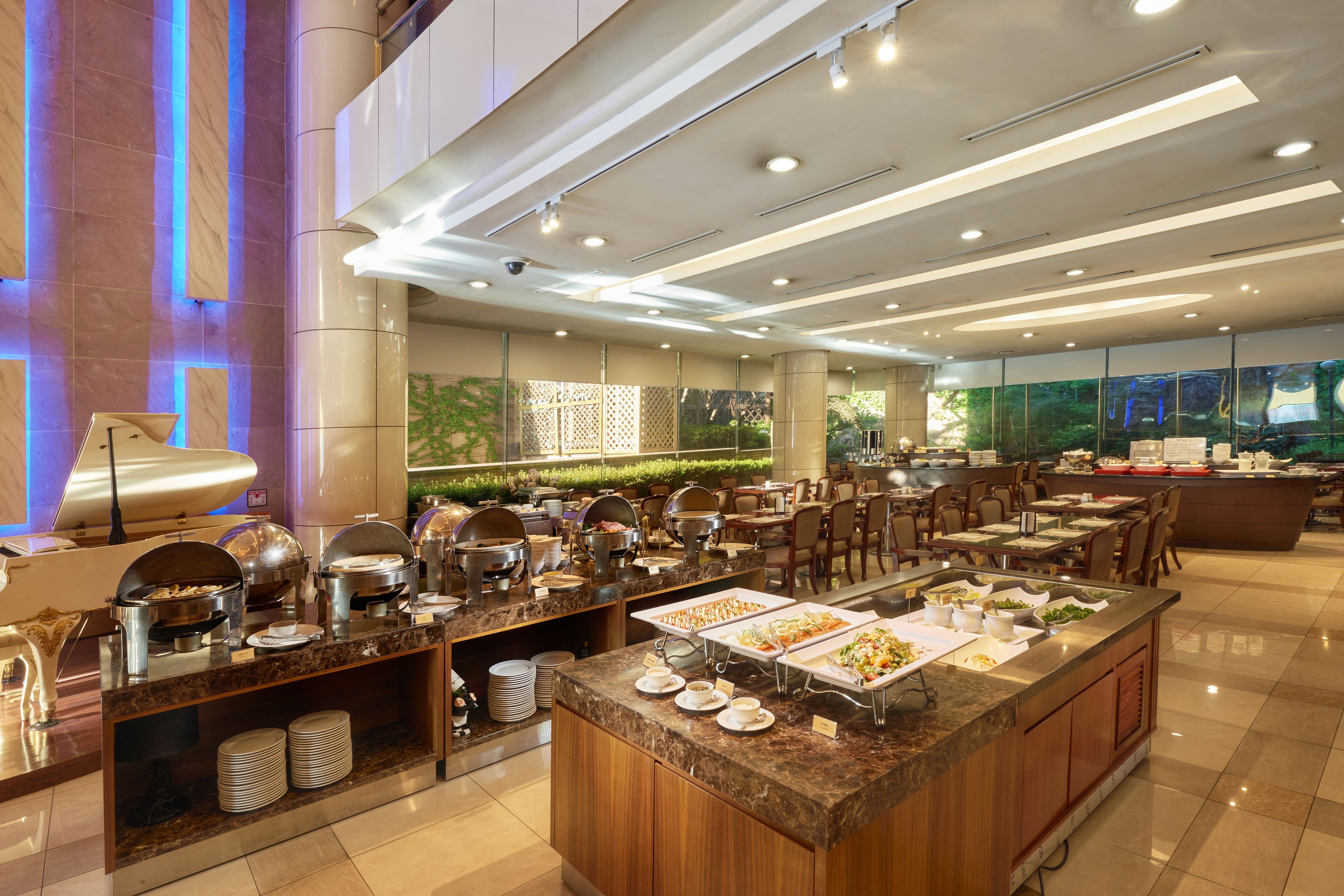 A buffet area with multiple serving stations, a large island with a variety of dishes, and a seating area with tables and chairs.