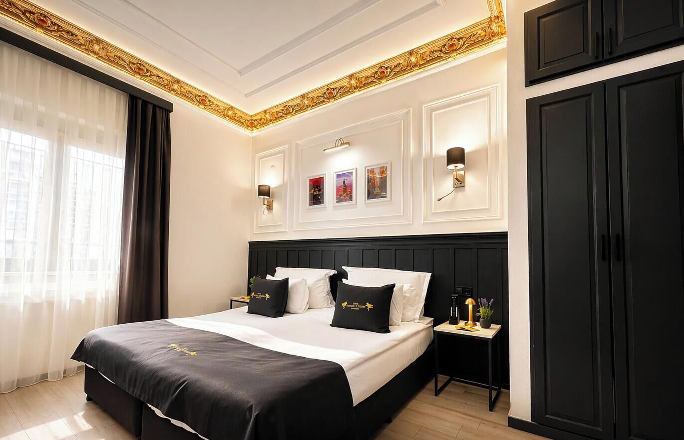 A hotel room with a large bed, a nightstand, a wardrobe, and wall-mounted lights.