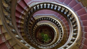 A spiral staircase with ornate railings and patterned carpet. - Grand Hotel Moderne (Lourdes)