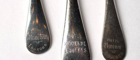 Three metal cutlery items with engraved text, likely from a hotel.