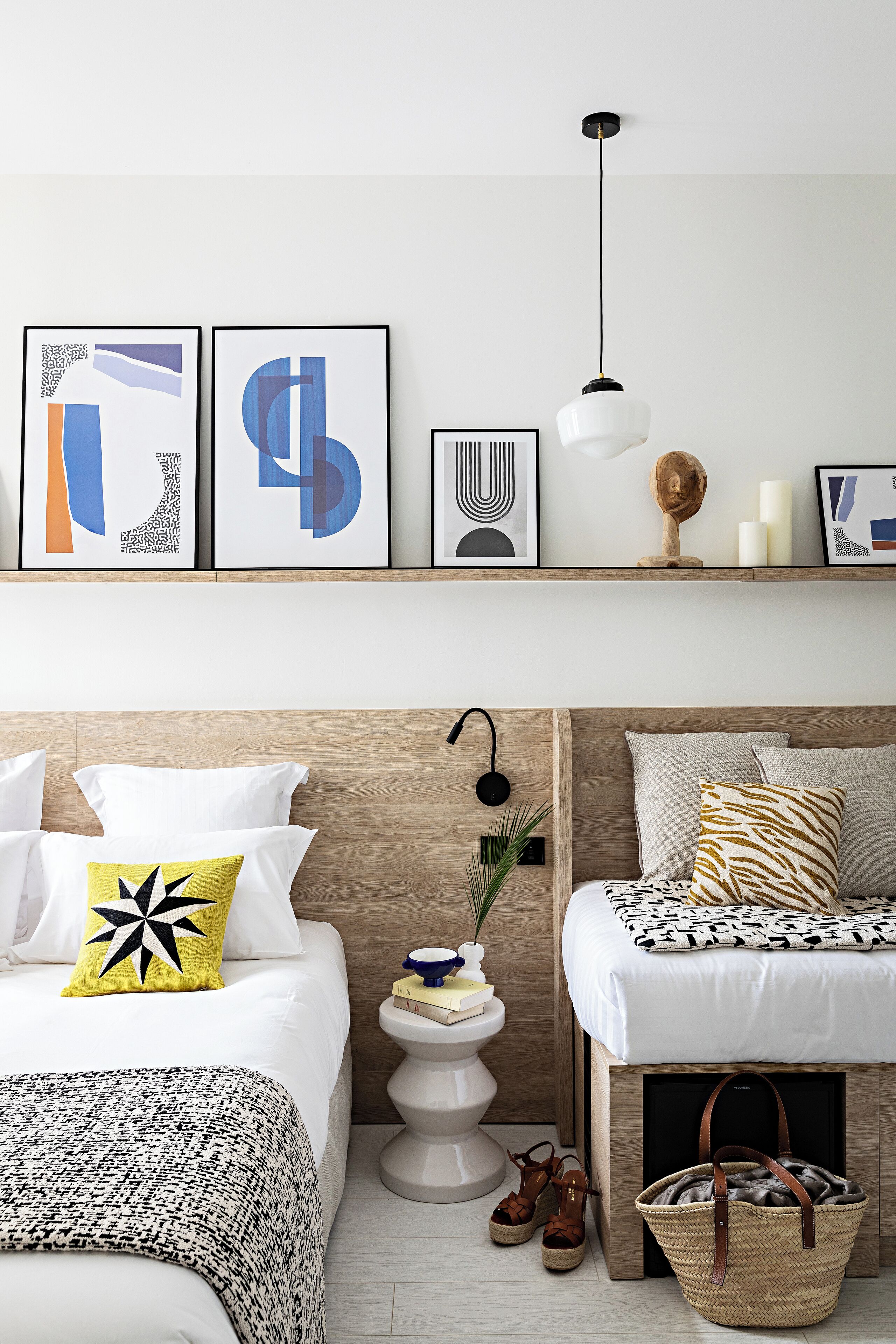 A bedroom with a bed, bedside table, lamp, and a hanging light fixture.