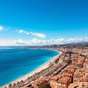 Paesaggio costiero con spiaggia, edifici e cielo sereno.