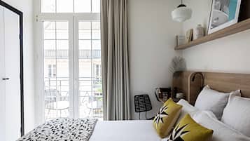 Habitación de hotel con cama, escritorio, silla, ventana con cortinas y vistas al exterior.