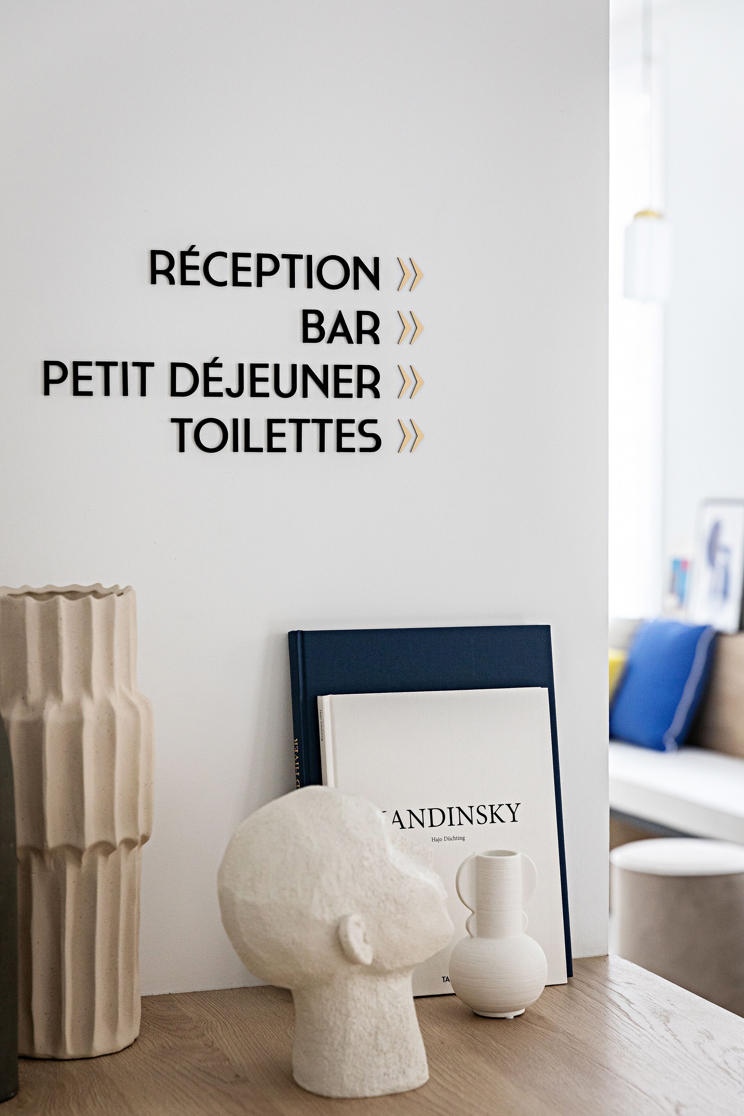 A reception area with a wall sign listing amenities: reception, bar, small dining area, and toilets.