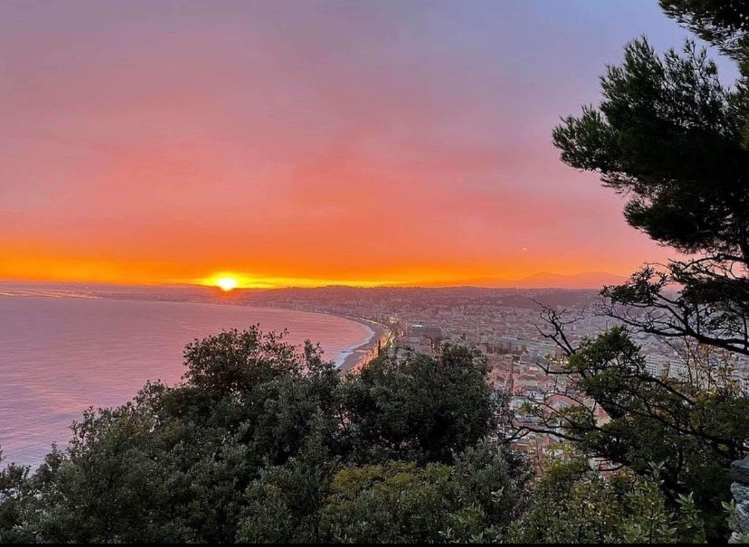 Un paisaje urbano costero al atardecer con vistas al océano y una carretera sinuosa.