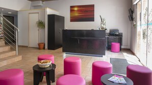 A reception area with a desk, a computer, a potted plant, and a painting of a sunset. - L'Esterel (Cannes)