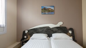A bedroom with a bed, a nightstand, a telephone, and a painting on the wall. - L'Esterel (Cannes)