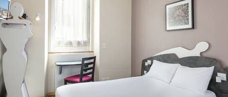 A bedroom with a bed, a desk, and a chair.
