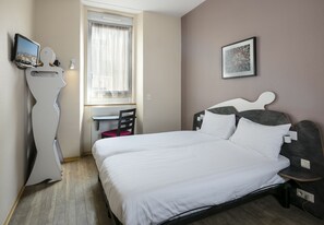 Een slaapkamer met een bed, een bureau en een stoel.
