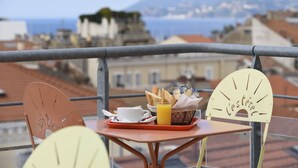 A balcony with a table set for breakfast, including bread, a cup, and a glass of orange juice. - L'Esterel (Cannes)