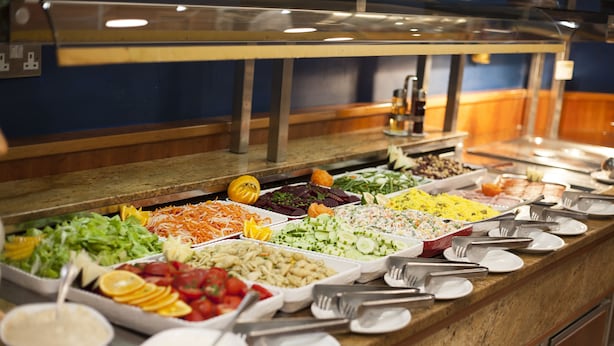 Een buffet met diverse keuze aan eten, waaronder salades, fruit en pasta.