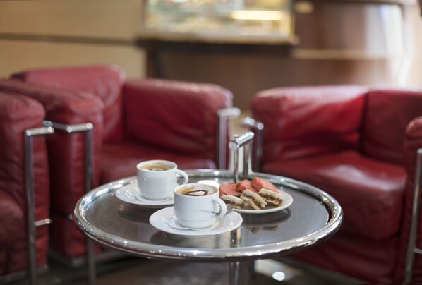 Una mesa redonda pequeña con dos tazas blancas de café y un plato de pasteles.