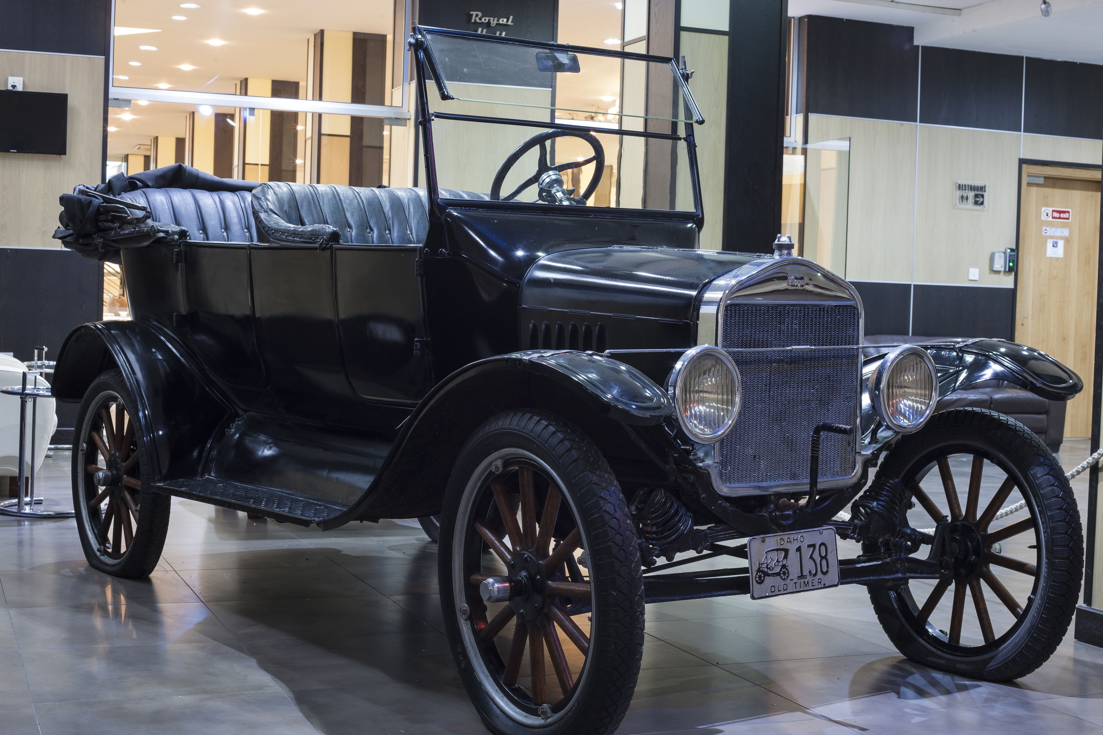 A vintage car exhibit in a museum with a reflective floor and modern interior.