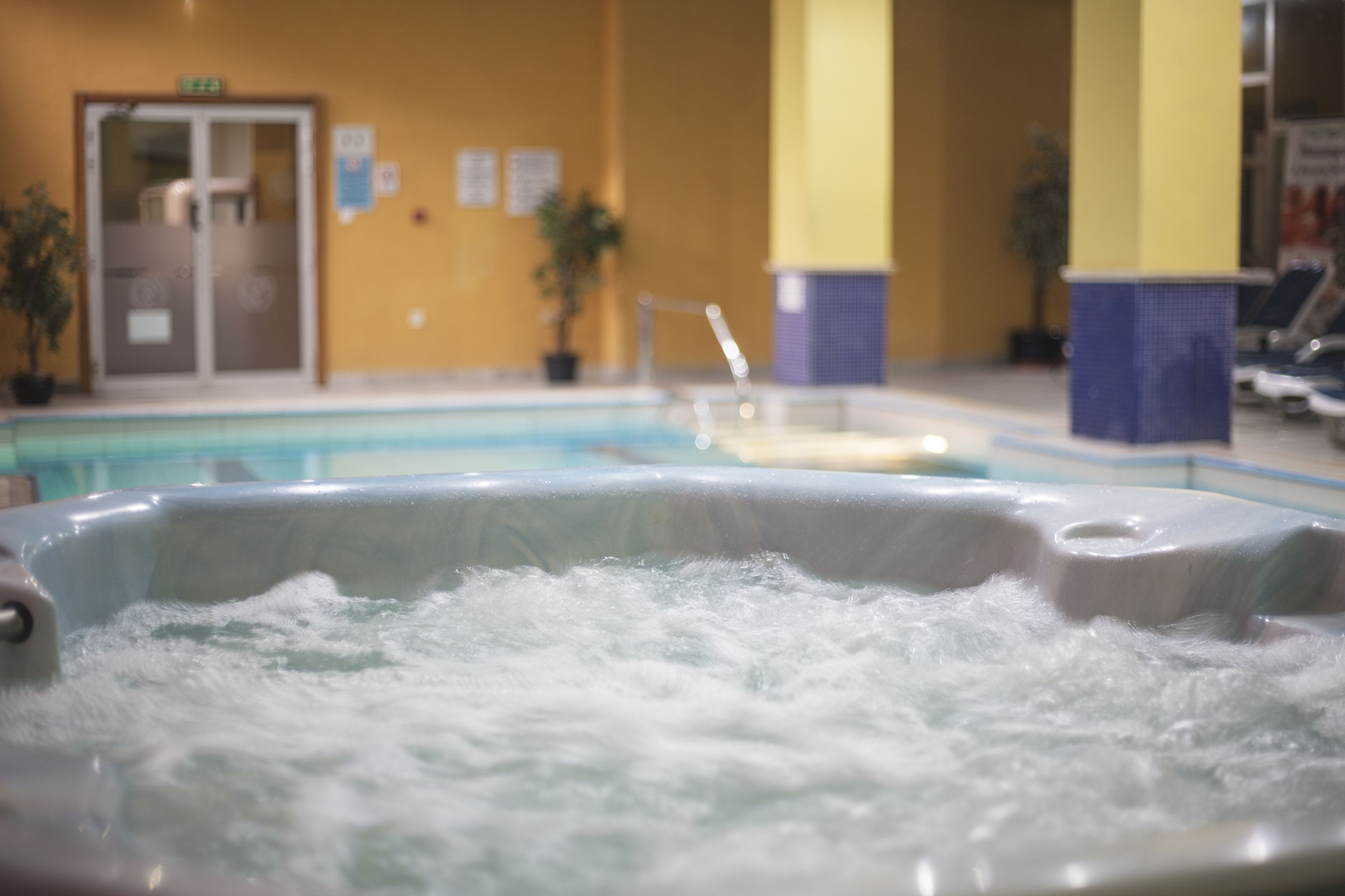Un jacuzzi con vista a una piscina y una puerta al fondo.