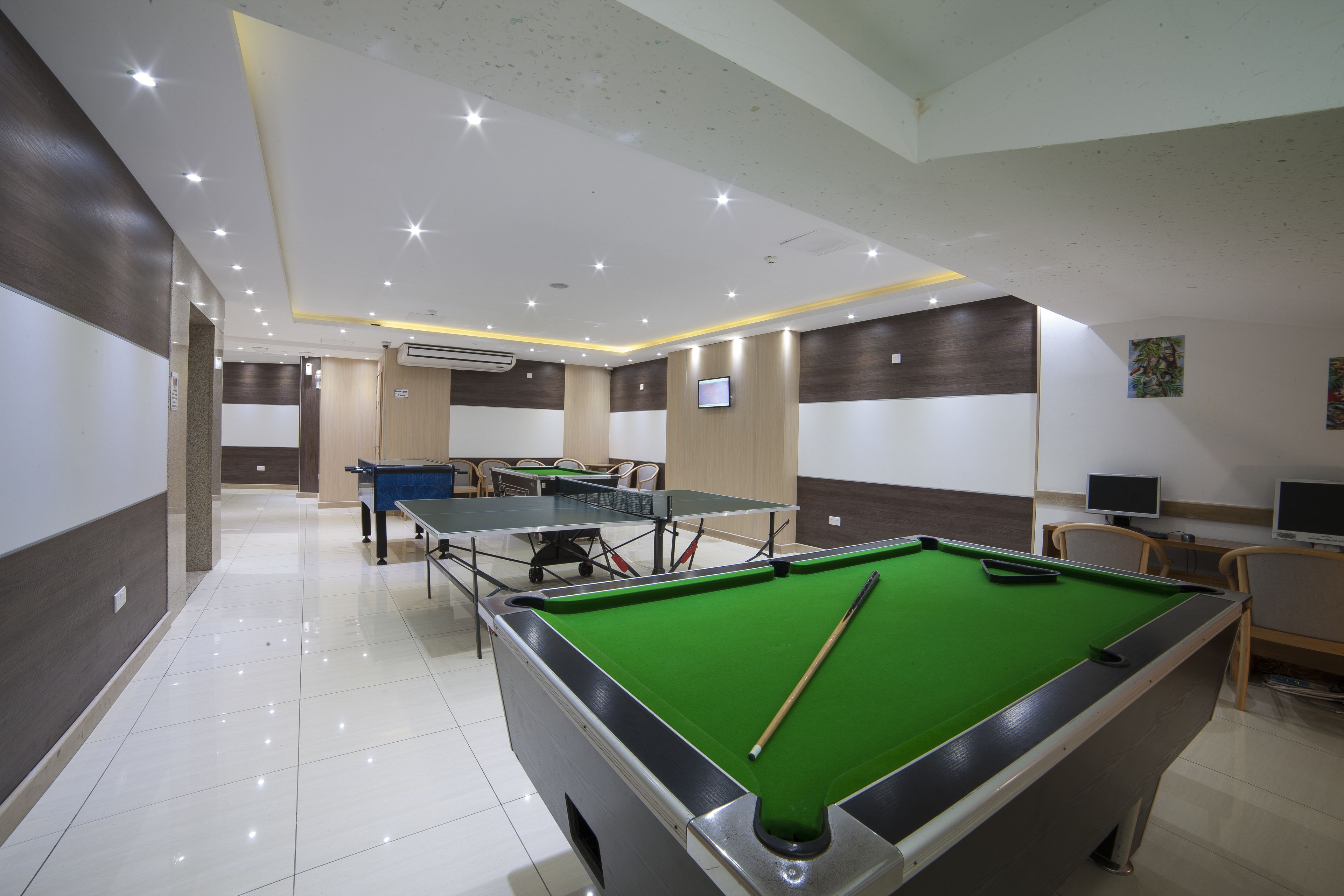 A billiards room with a pool table, a second table, and two chairs.