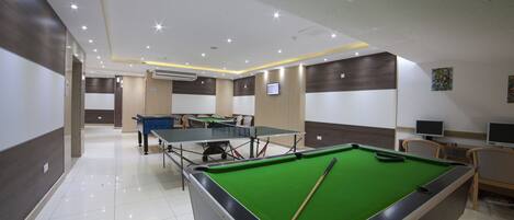A billiards room with a pool table, a second table, and two chairs.