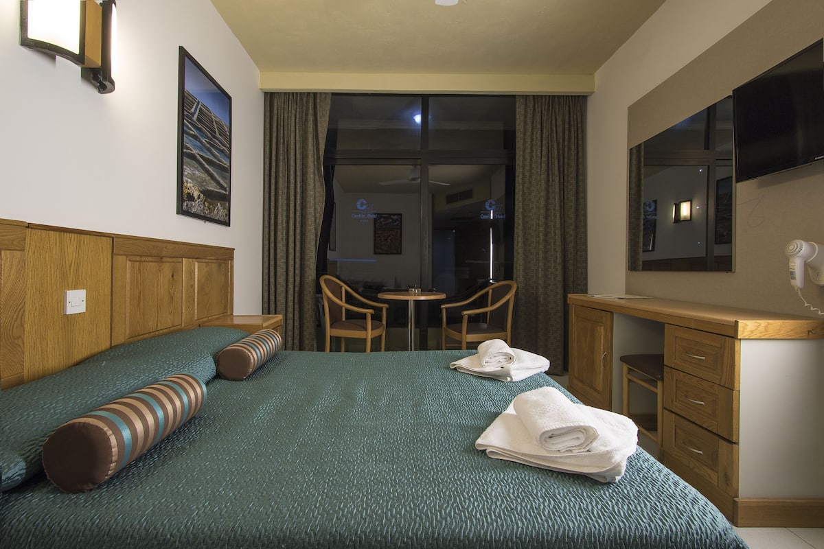 Una habitación de hotel con cama, escritorio, silla y televisor.