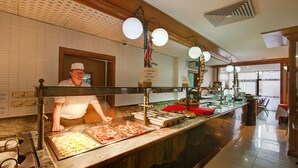 A buffet counter with various food items, a sink, and a person behind the counter. - Canifor Hotel (St. Paul's Bay)