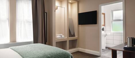 A hotel room with a bed, a walk-in closet, a television, and a bathroom.
