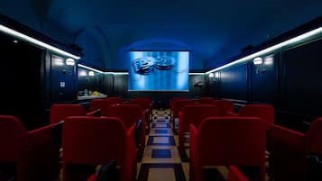 A cinema with red seats, a central aisle, and a large screen displaying film reels.