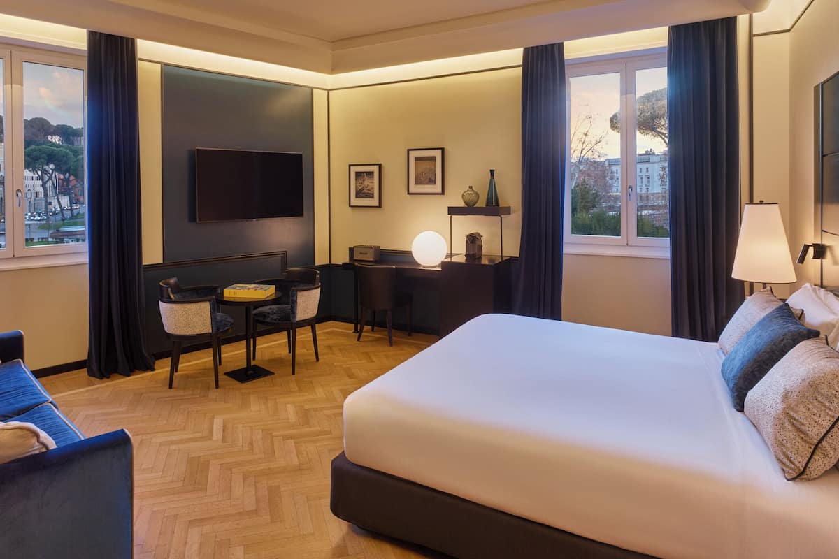 Une chambre d’hôtel avec un lit, un bureau, une chaise, une télévision et une vue sur la ville.