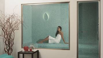 Bathroom features a glass shower enclosure, a small table, and a decorative plant.