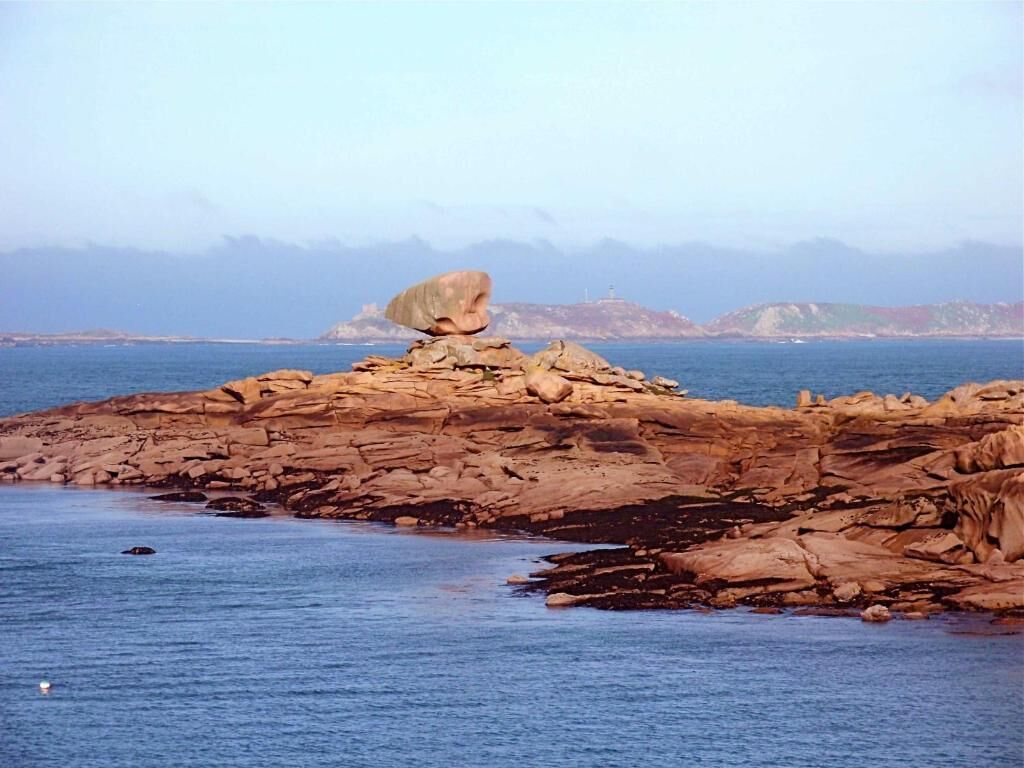 A rocky coastline with a prominent boulder in the center.