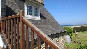 A house with a stone exterior, a wooden staircase, and a view of the sea. - Hôtel Les Sternes  (Louannec)