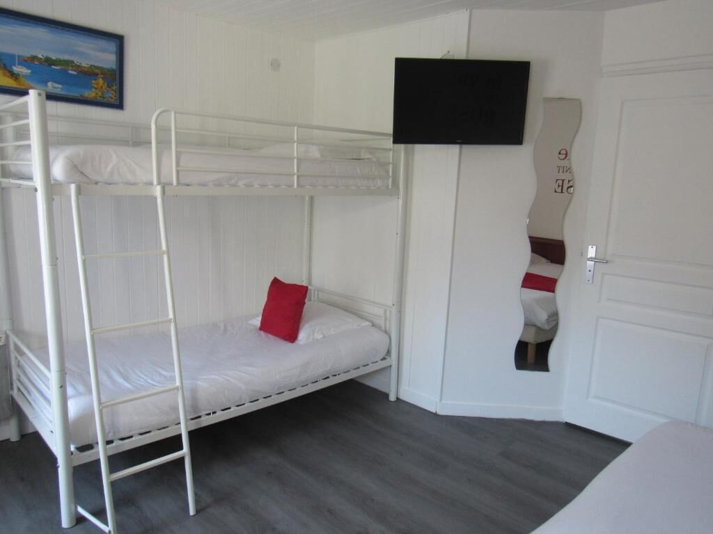Een slaapkamer met stapelbed, een televisie aan de muur en een deur met een handdoek.