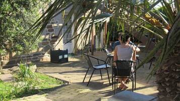 Een terras met stenen vloer, tuinmeubilair en een stenen muur.